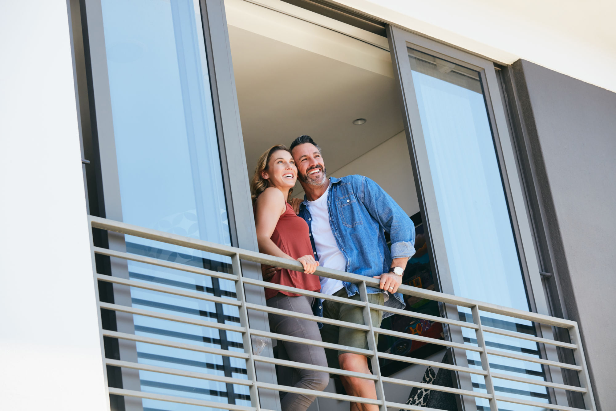 Shot of a happy couple standing on the balcony of their home