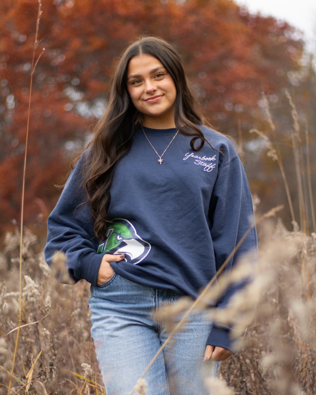 Madison Sylvester, scholarship recipient, standing in a patch of tall grass wearing a navy blue, Heritage High School sweatshirt
