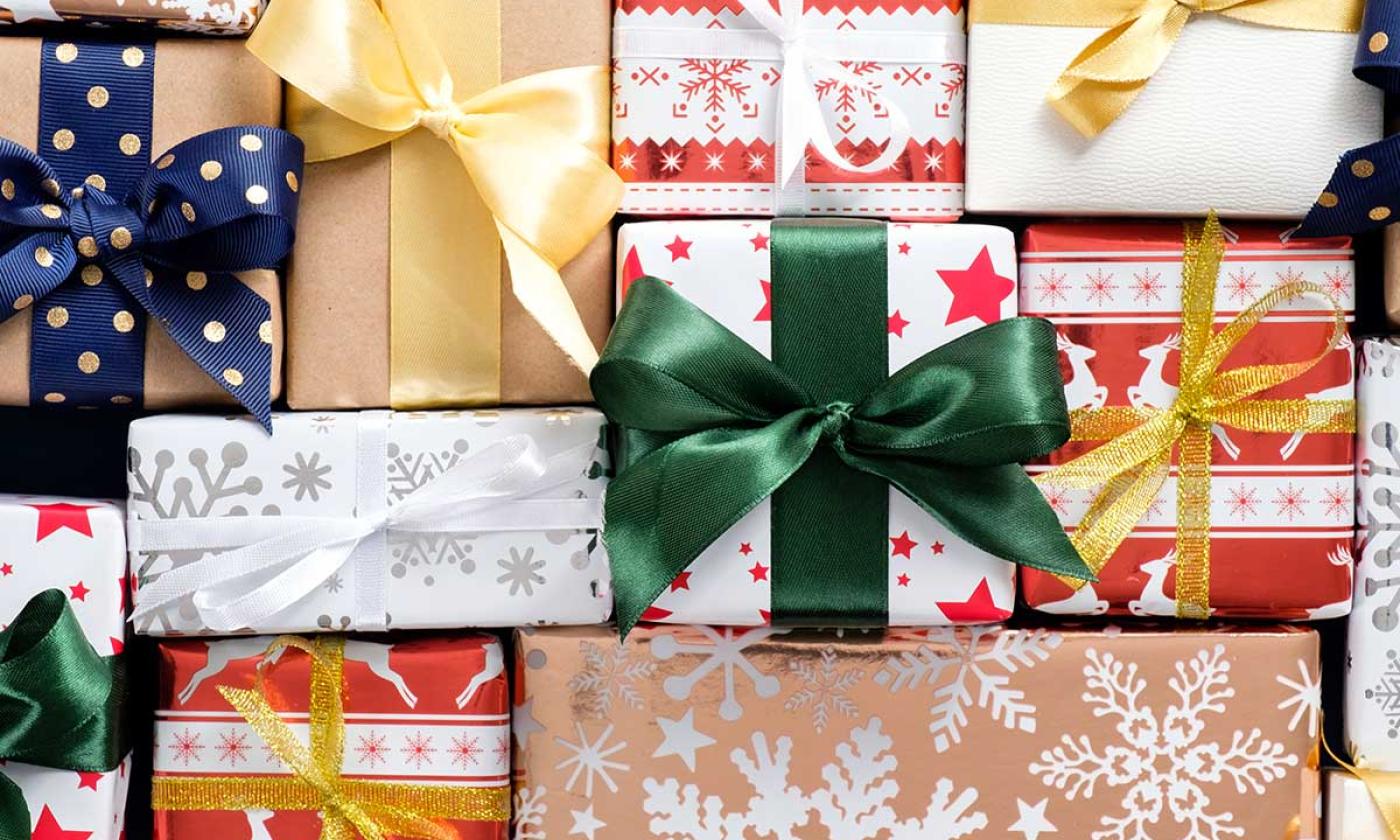 Top-down view of gifts wrapped in winter wrapping paper and tied with bows arranged in a grid.