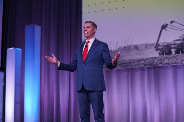 MFB President Ben LaCross speaking with his arms outstretched on the stage of the 2025 MFB State Annual Meeting.
