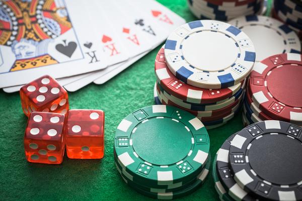 Close-up of a card table arranged with cards, poker chips,and dice.