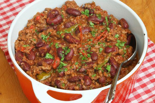 Close-up of a pot of chili on a checkered tablecloth.