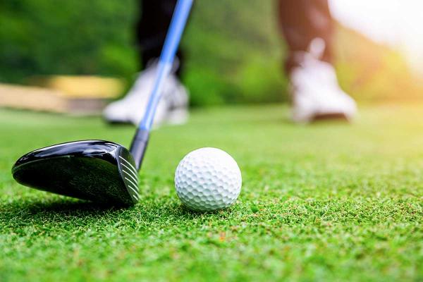 Low angle of a person preparing to drive a golf ball on a golf course.