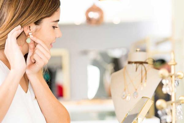 Woman trying on earrings at jewelry store.