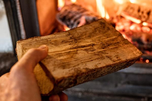 Putting a piece of wood into a woodstove.