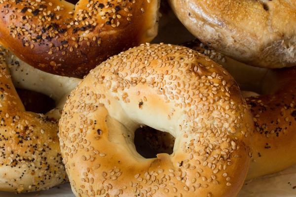 A paper bag full of a variety of bagel types.