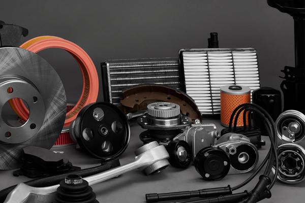 An assortment of new car parts arranged against a grey backdrop.