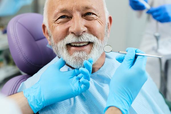 Happy senior man getting dental treatment at dentist's office.