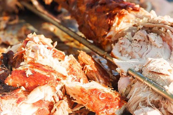 Close-up of a person carving a whole-hog roast.