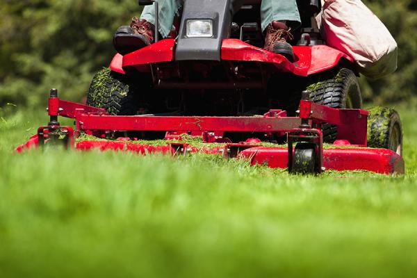 A man using a riding mower on a lawn.