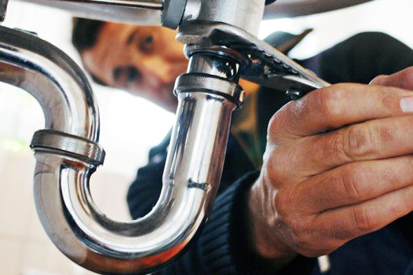 Close-up of plumber repairing sink with a wrench.
