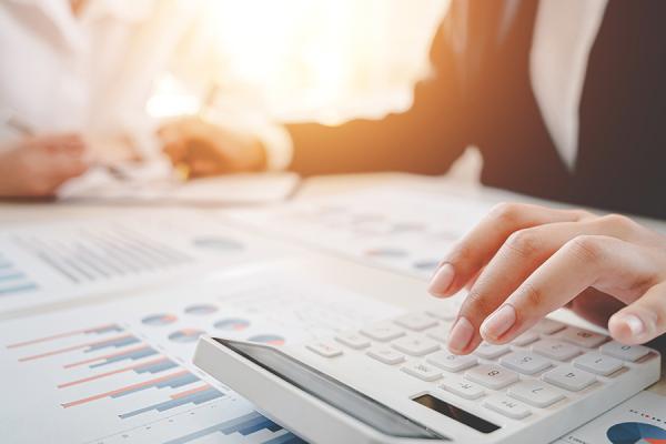 Woman using a calculator to prepare taxes documents for her client.