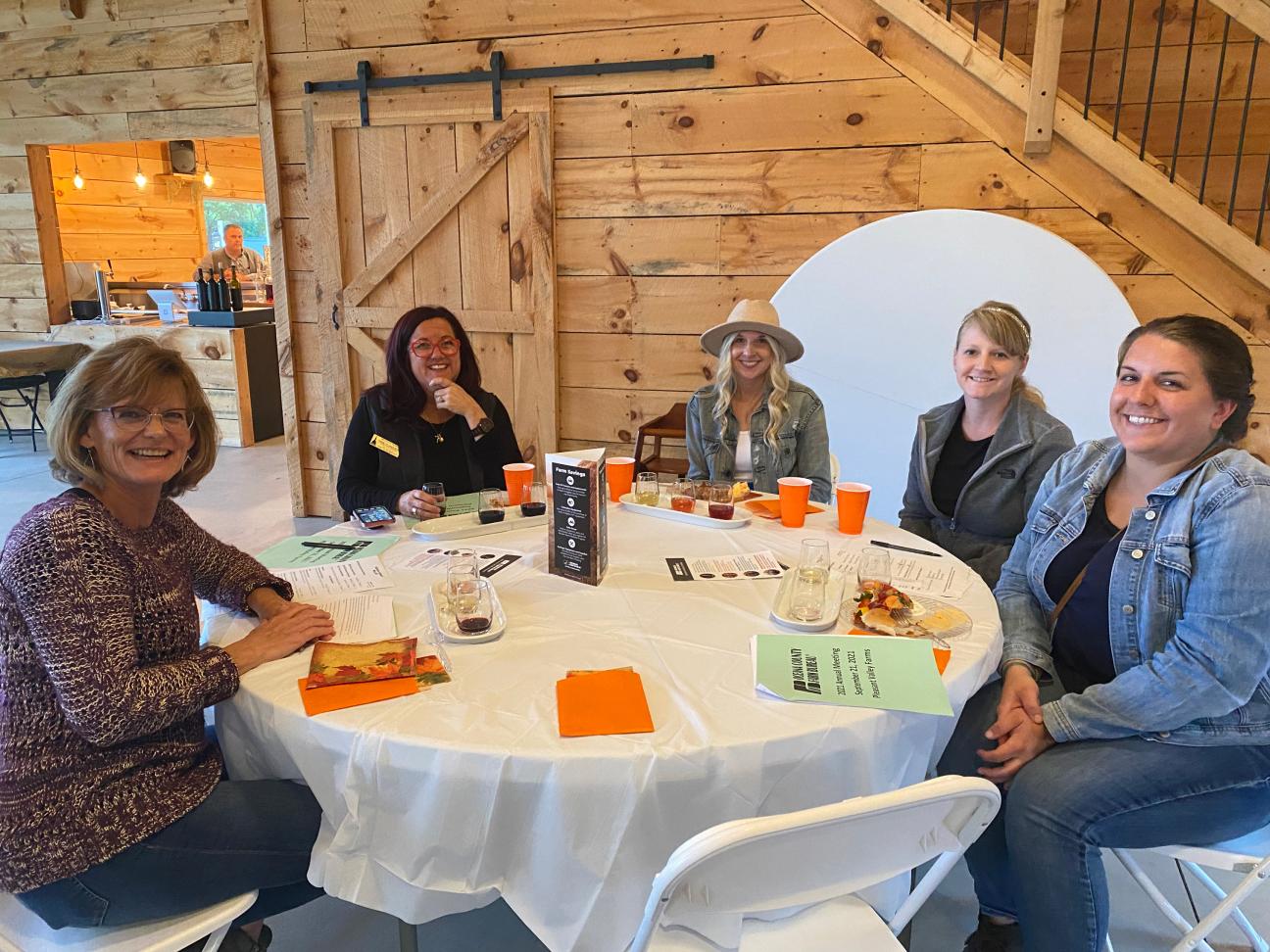 Four Oceana County Farm Bureau members smiling at the camera while seated at a round table in a barn at the 2021 Oceana County Farm Bureau Annual Meeting.