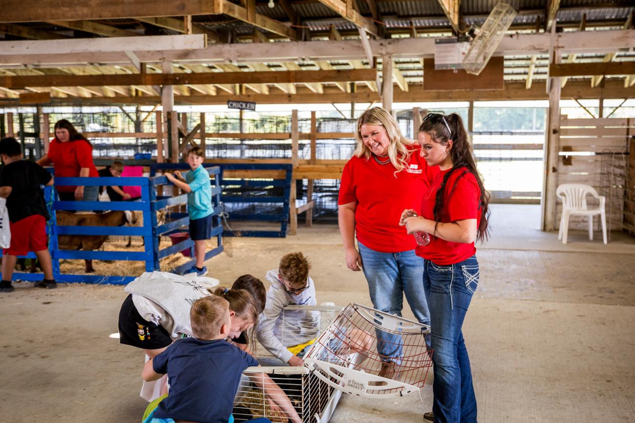 YF Award winner Jasmine McNary smiling while showing a group of students some rabbits in a cage.
