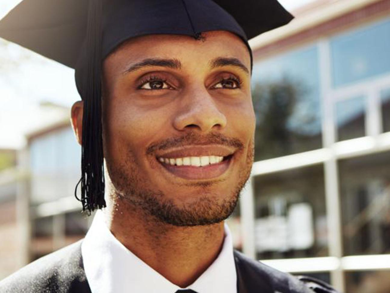 The face of a smiling man wearing a cap and gown.