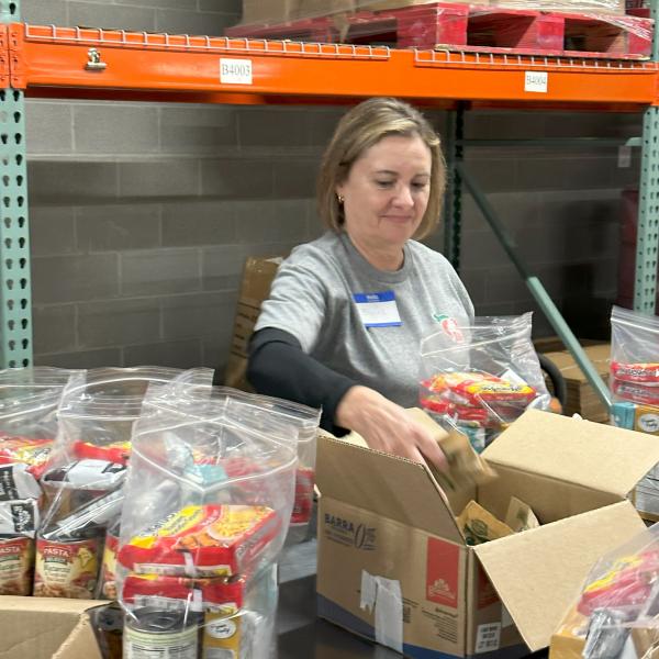 A Farm Bureau employee loading boxes with non-perishable food items for those in need in a warehouse.