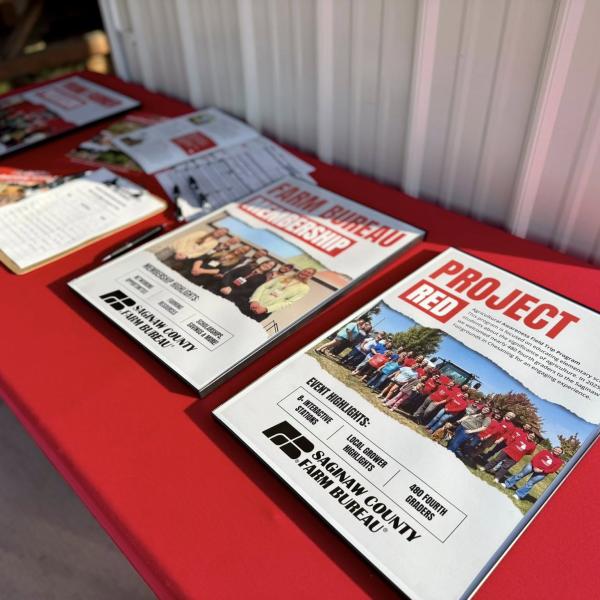 Posters on a red registration table highlighting the achievements from the past year. Featured are "Project RED", "Membership", and "Young Farmers"