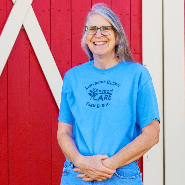 Portrait of Presidential Volunteer of the Year Award winner Barb Parker smiling at the camera while standing in front of a red barn door.