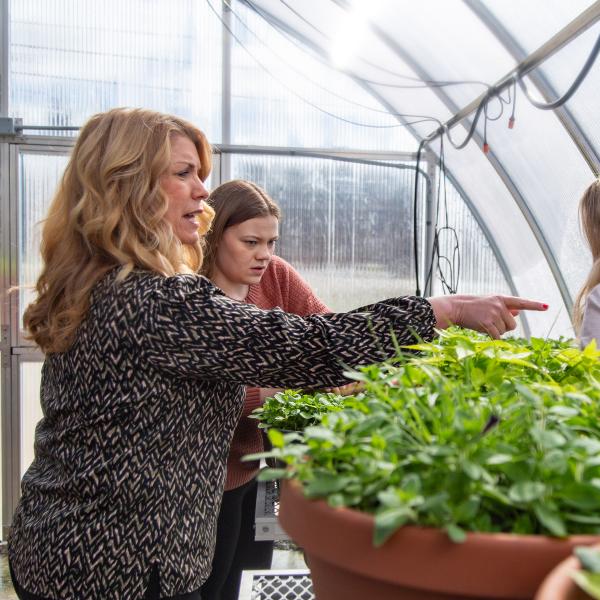Educator of the Year Katie Courtade gesturing while instructing students in a greenhouse.