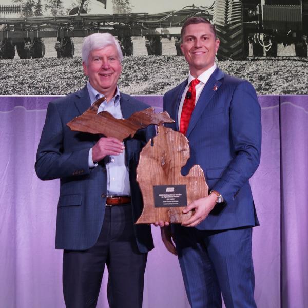 MFB President Ben LaCross presenting former governor Rick Snyder with the Distinguished Service to Agriculture Award on stage at the 2025 State annual Meeting.