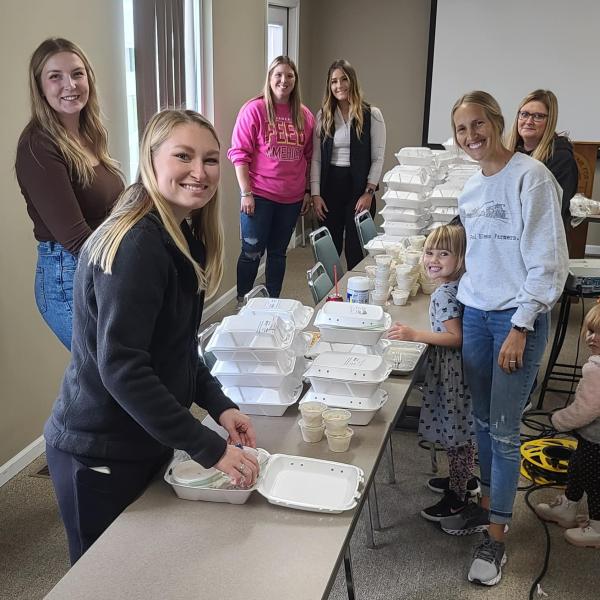 A group of young farmers smiling at the camera while packing meals for those in need.