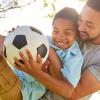 Child holding soccer ball with father