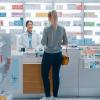 A woman standing at the counter of a pharmacy speaking with the pharmacist