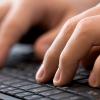 Close-up of hands typing on laptop.